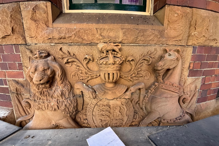 a sandstone coat of arms of a dragon and horse with a eroded lion