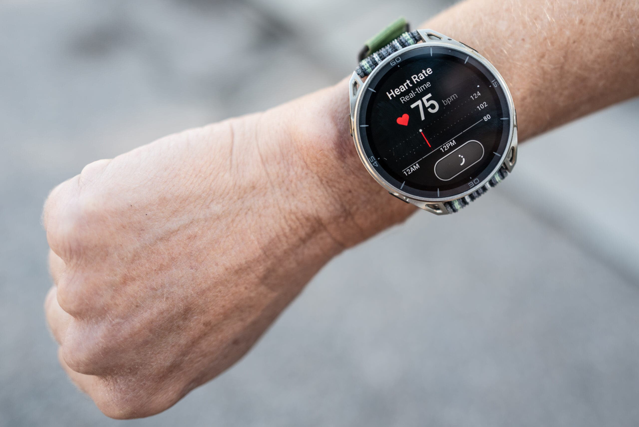 Amazfit Cheetah 2 Ultra smartwatch on a runner's wrist showing a real-time heart rate of 75 bpm on its round display, with a green and gray woven nylon band.