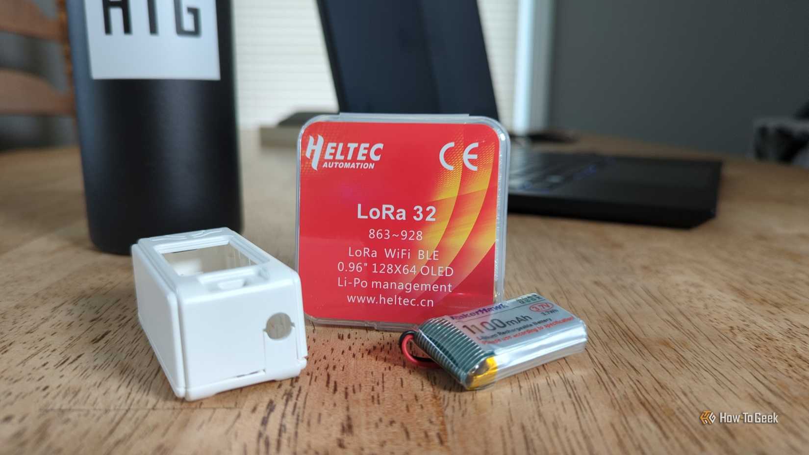 A LoRa 32 package with a case and a battery next to it.
