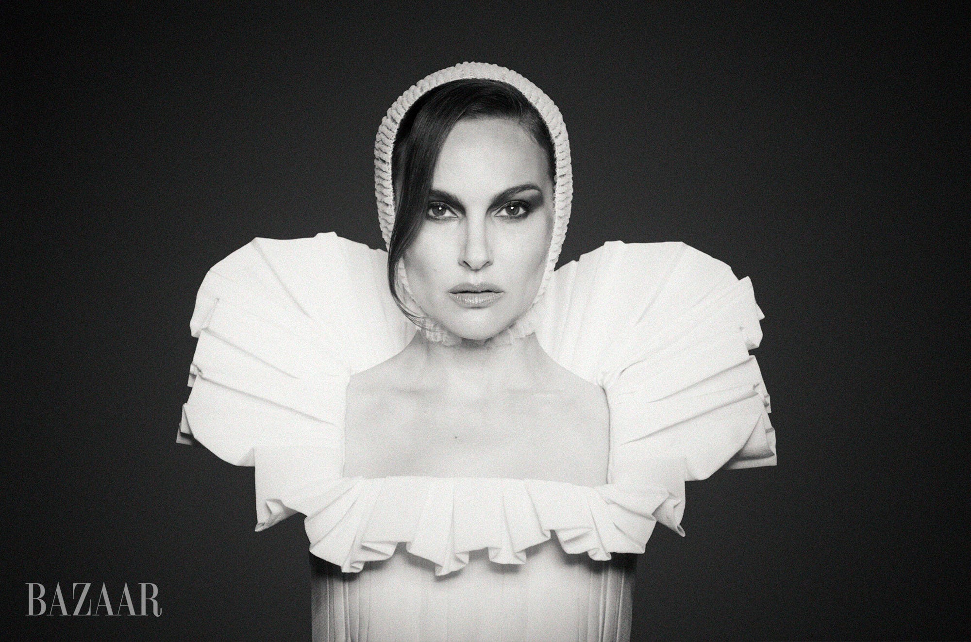 Black and white portrait of a woman in a striking white outfit with dramatic ruffled shoulders and a bonnet. Black and white portrait of a woman in a striking white outfit with dramatic ruffled shoulders and a bonnet.