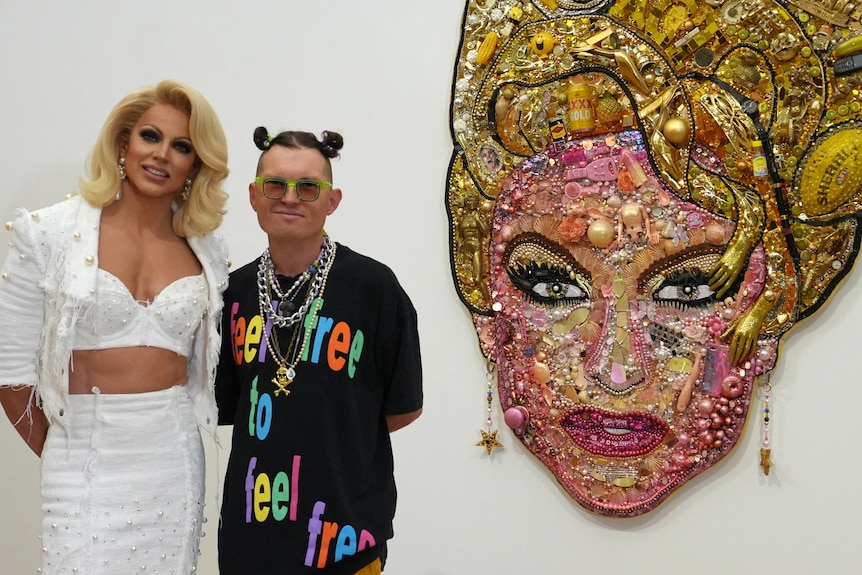 Courtney Act and artist Paul Yore stand in front of Yores work of Act.