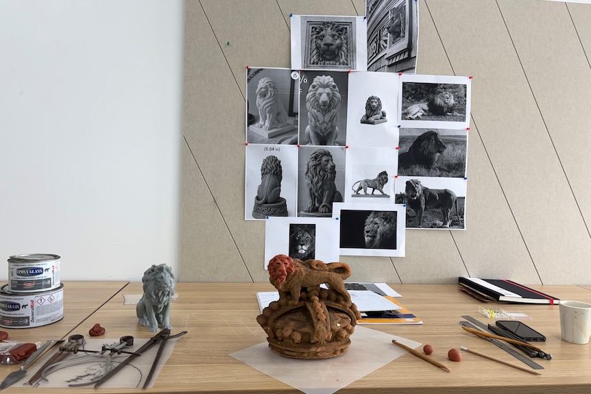a model lion on a table surrounded by black and white photos of lions