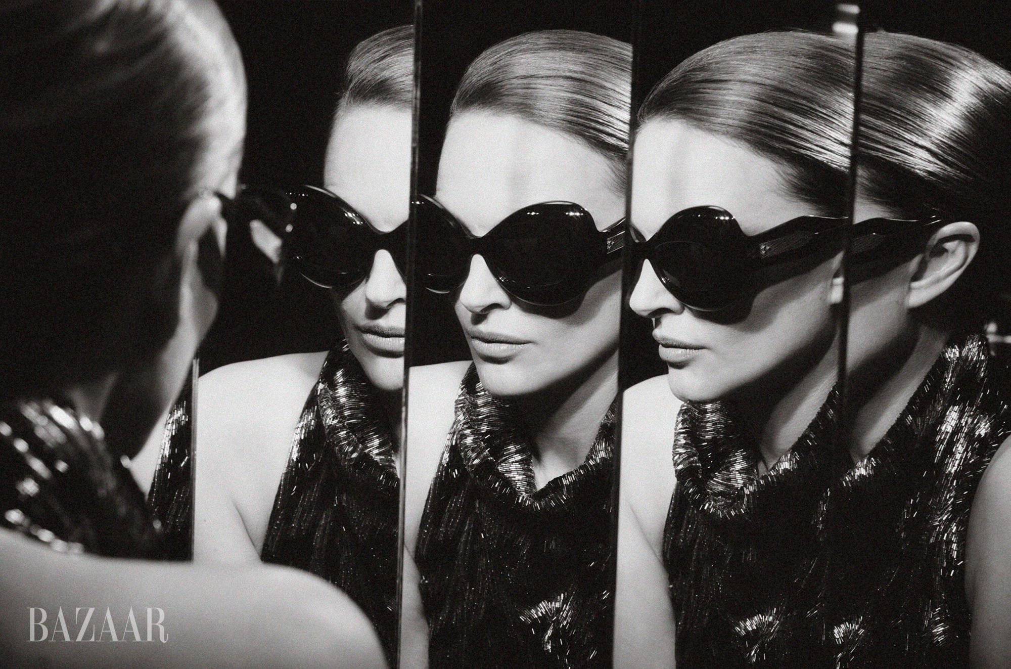 A woman in oversized sunglasses reflected in multiple mirrors, showcasing a glamorous black and white aesthetic. A woman in oversized sunglasses reflected in multiple mirrors, showcasing a glamorous black and white aesthetic.