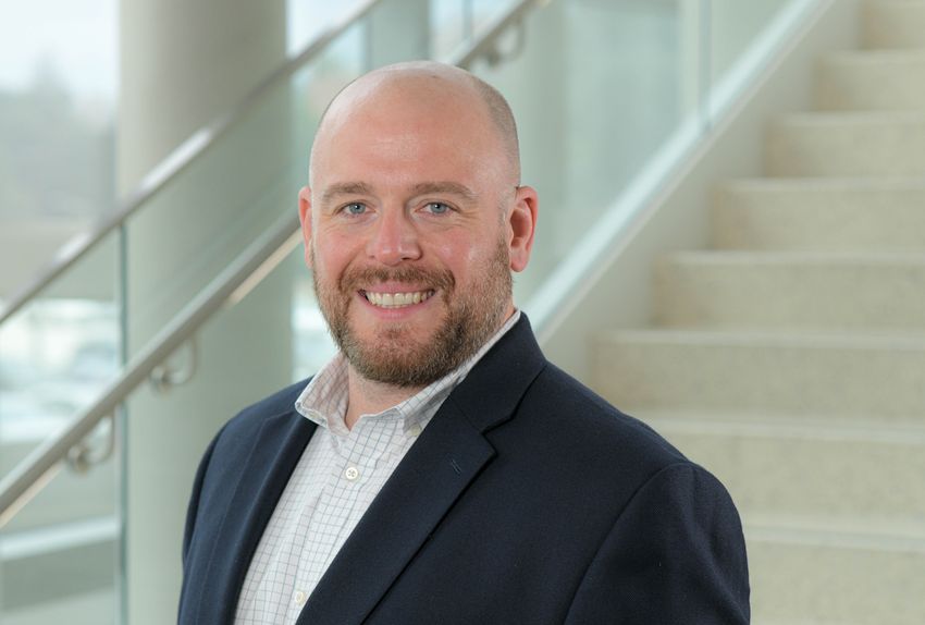 Geneticist Michael Lodato wears a dark suit jacket and stands in front of a staircase in this headshot photo.