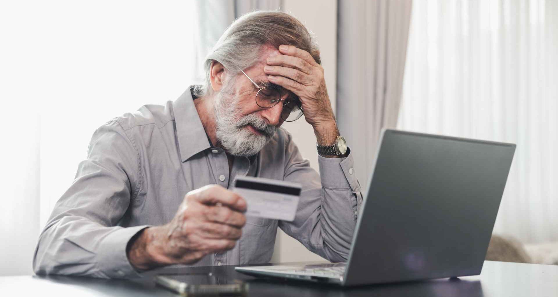 Worried senior man holding credit card