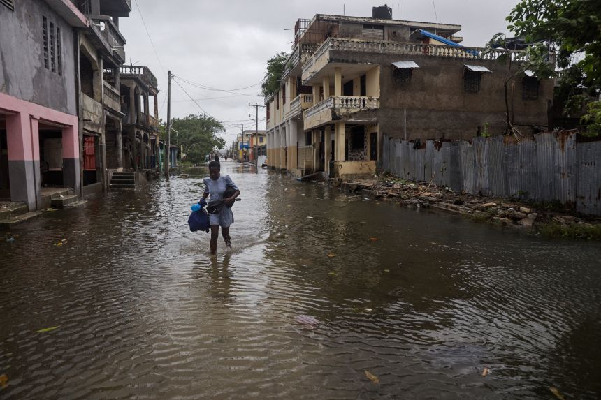 A woman holds her belongings after heavy rains flooded parts of Les Cayes, Haiti, Wednesday.