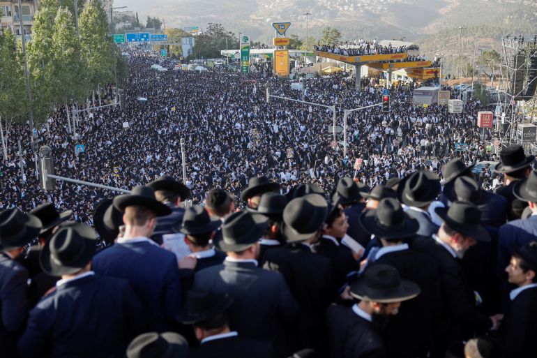 Ultra-Orthodox Jewish men gather on and below the Chords Bridge during the "Million Man" protest against Israeli military conscription [Ammar Awad/Reuters]