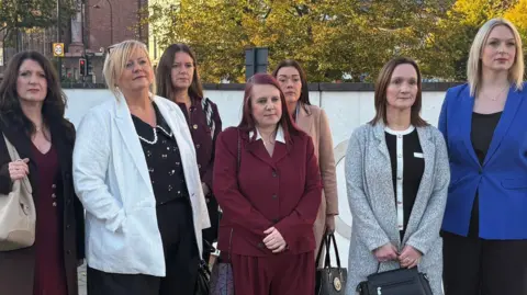 PA Media Seven nurses standing outside the tribunal centre in Newcastle. They are wearing smart outfits and serious expressions.
