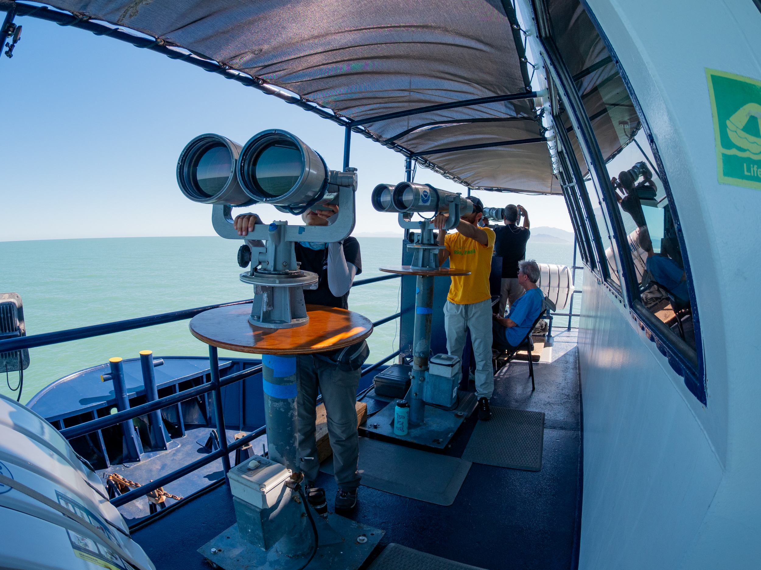people aboard a boat looking into big binoculars