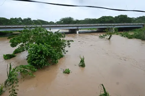 AFP via Getty Images The Rio Cobre comes out of its banks near St. Catherine, Jamaica, shortly before Hurricane Melissa made landfall on 28 October 2025.