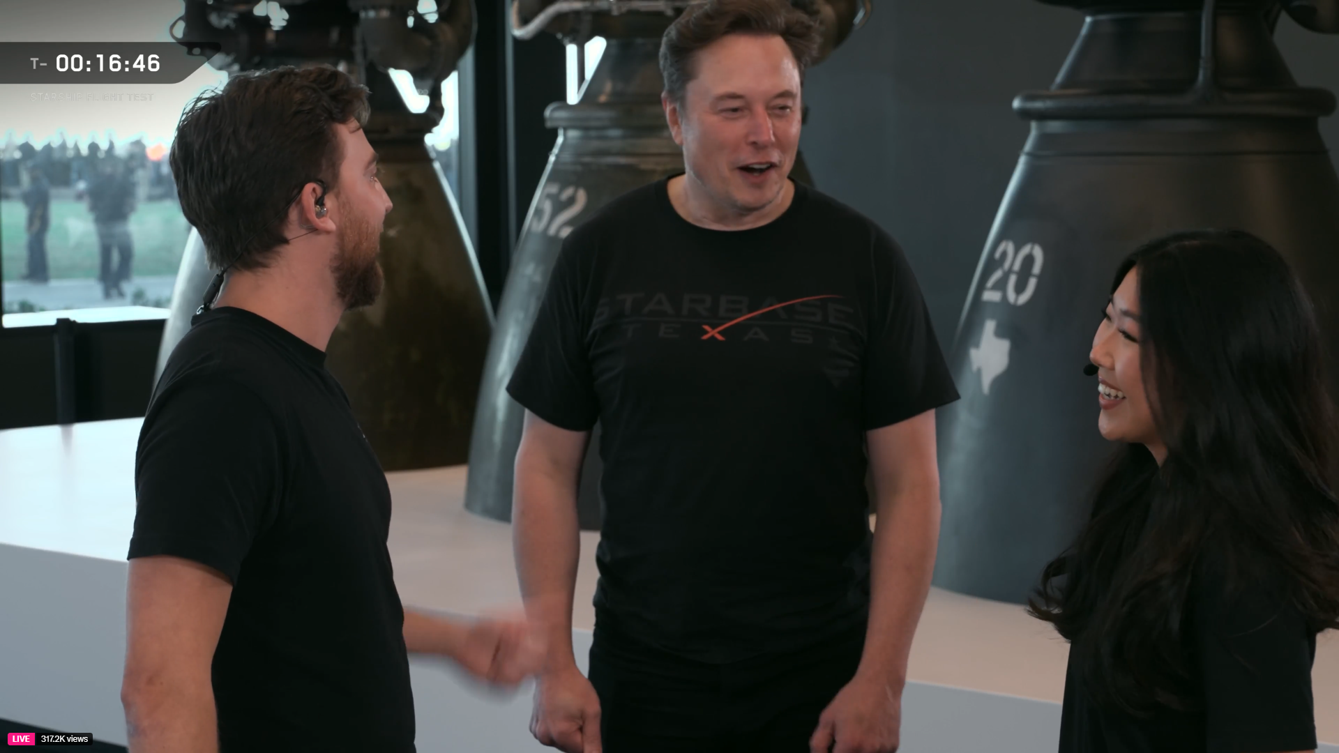 SpaceX CEO Elon Musk smiles while talking with a man and woman