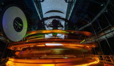 A long exposure image shows rings of glowing lights inside the dome of an observatory with streaks through the open dome showing the stars