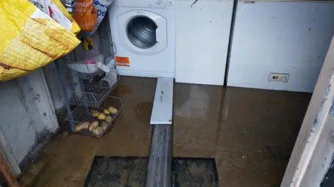 LDRS Sewage pictured in a garage. The sewage can be seen on the floor alongside two planks leading to the washing machine. 