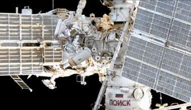 an exterior view of a space station includes two spacesuited cosmonauts at work during a spacewalk