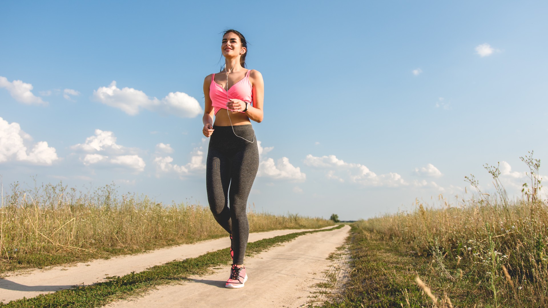 Woman in activewear walking in nature smiling on a sunny day
