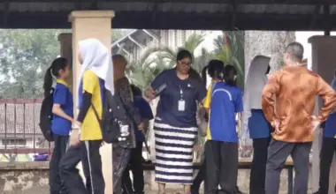 A teacher from SMK Bandar Utama Damansara 4 uses a metal detector to screen students before they enter the school compound