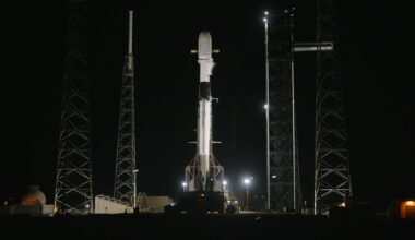 A SpaceX Falcon 9 rocket standing fully fueled on a launch pad at night.
