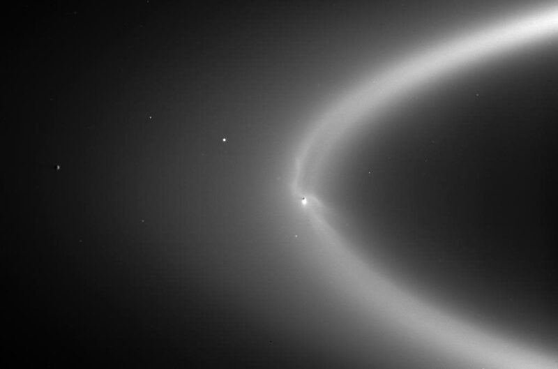 A wispy white ring in space with a little moon that has haze around its bottom section.