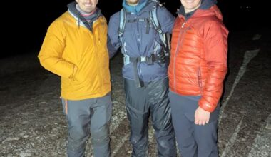 Three men in cold-weather gear, two sporting headlamps.