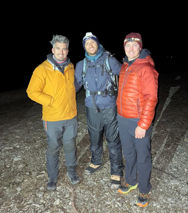 Three men in cold-weather gear, two sporting headlamps.