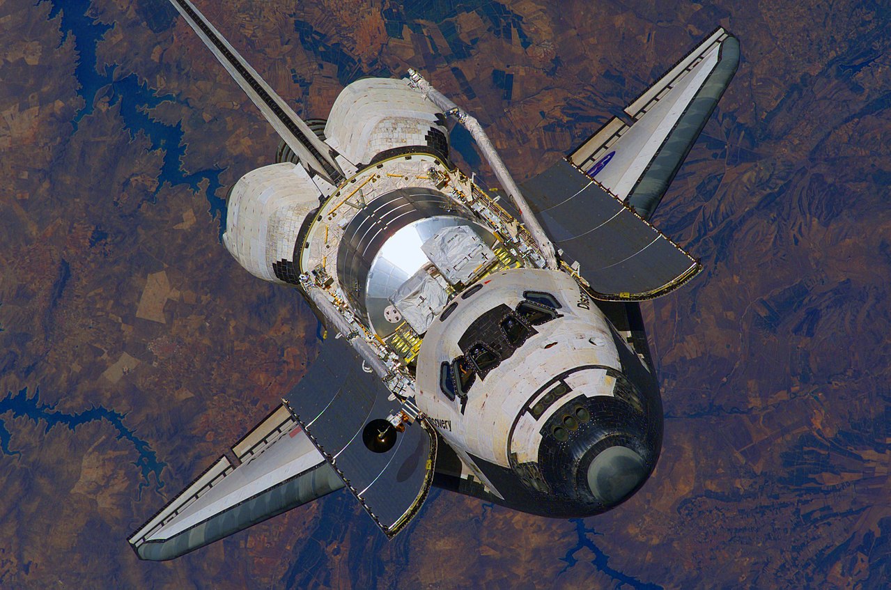 A black and white space shuttle floats above Earth in low-Earth orbit