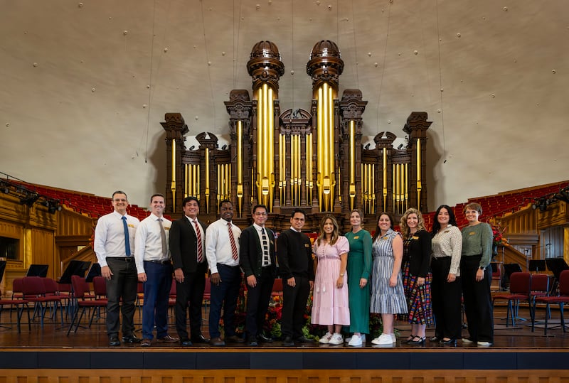 Global members of The Tabernacle Choir at Temple Square pose in front of the organ pipes in the Tabernacle as they discuss their musical histories and how they feel about the opportunity to be members of the choir, during an interview in the Tabernacle in Salt Lake City on Tuesday, Sept. 23, 2025.