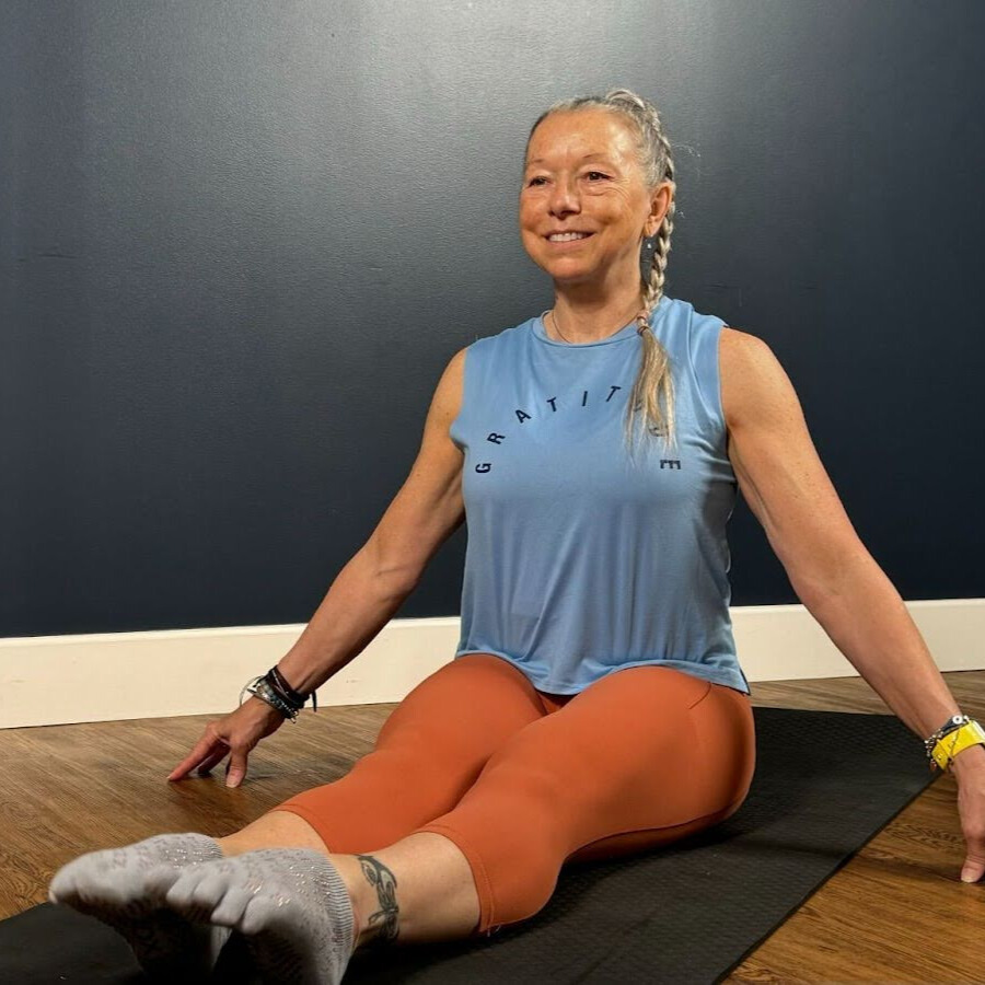 Woman sits cross-legged on mat demonstrating wrist movement