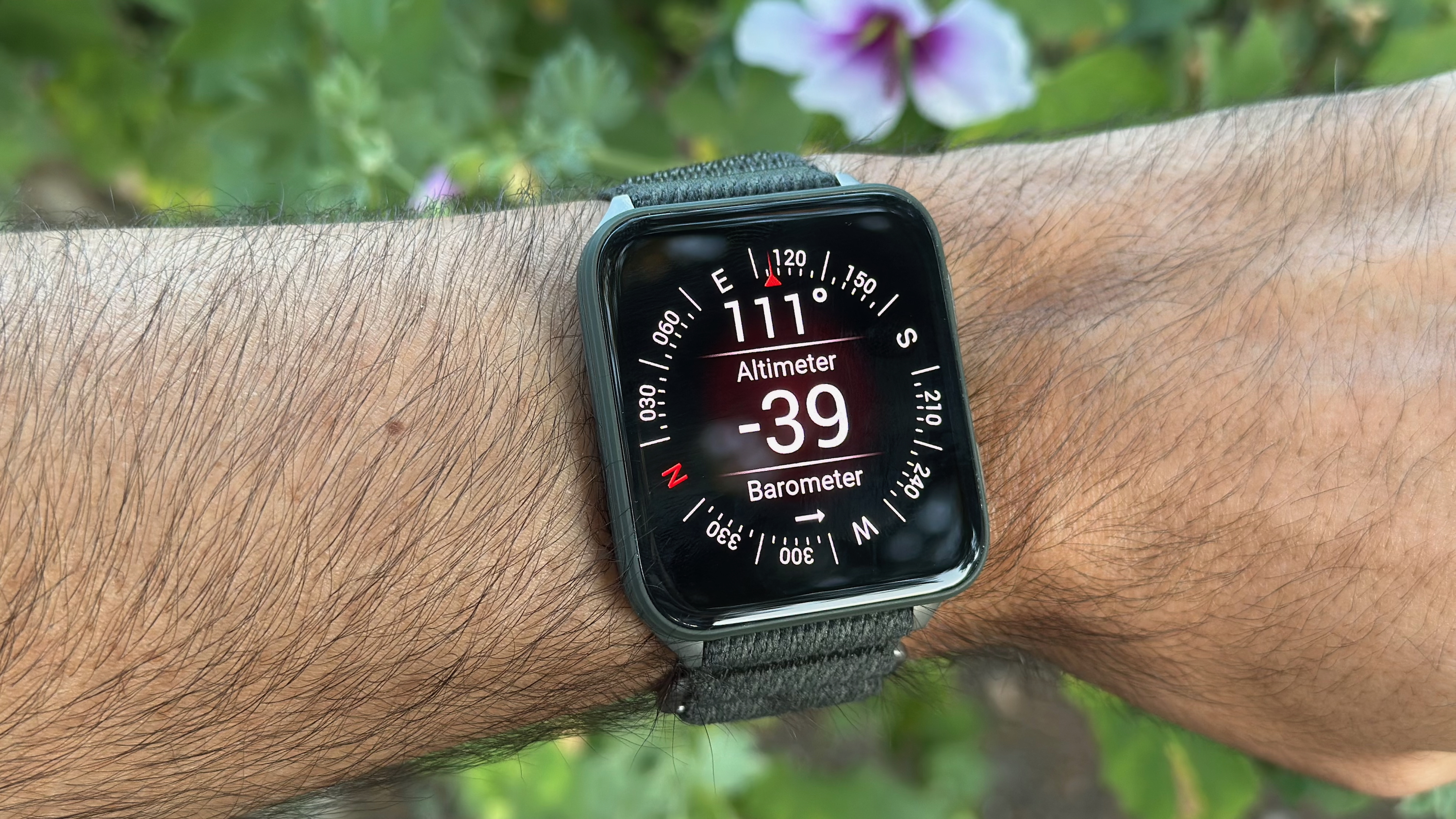 The Garmin Venu X1 worn on a wrist showing the ABC app with a compass, altimeter, and barometer data.