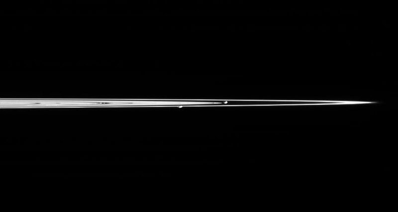 Edge-on view of Saturn's rings and 2 tiny, rocky moons.