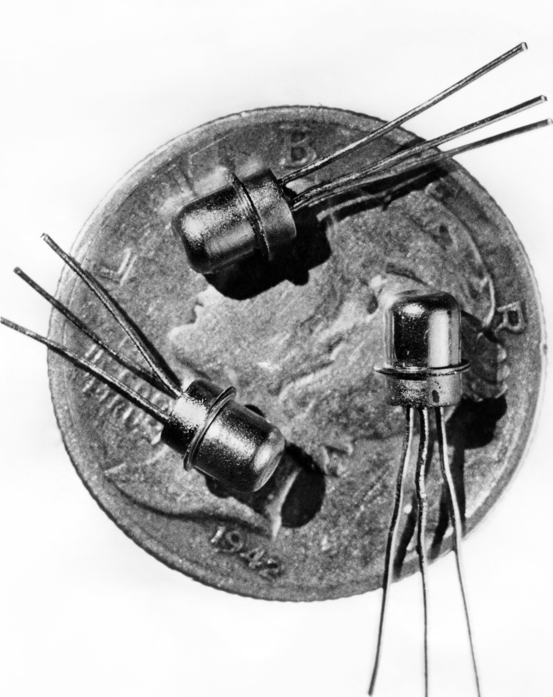 a close-up of three miniature M-1 transistors against a dime