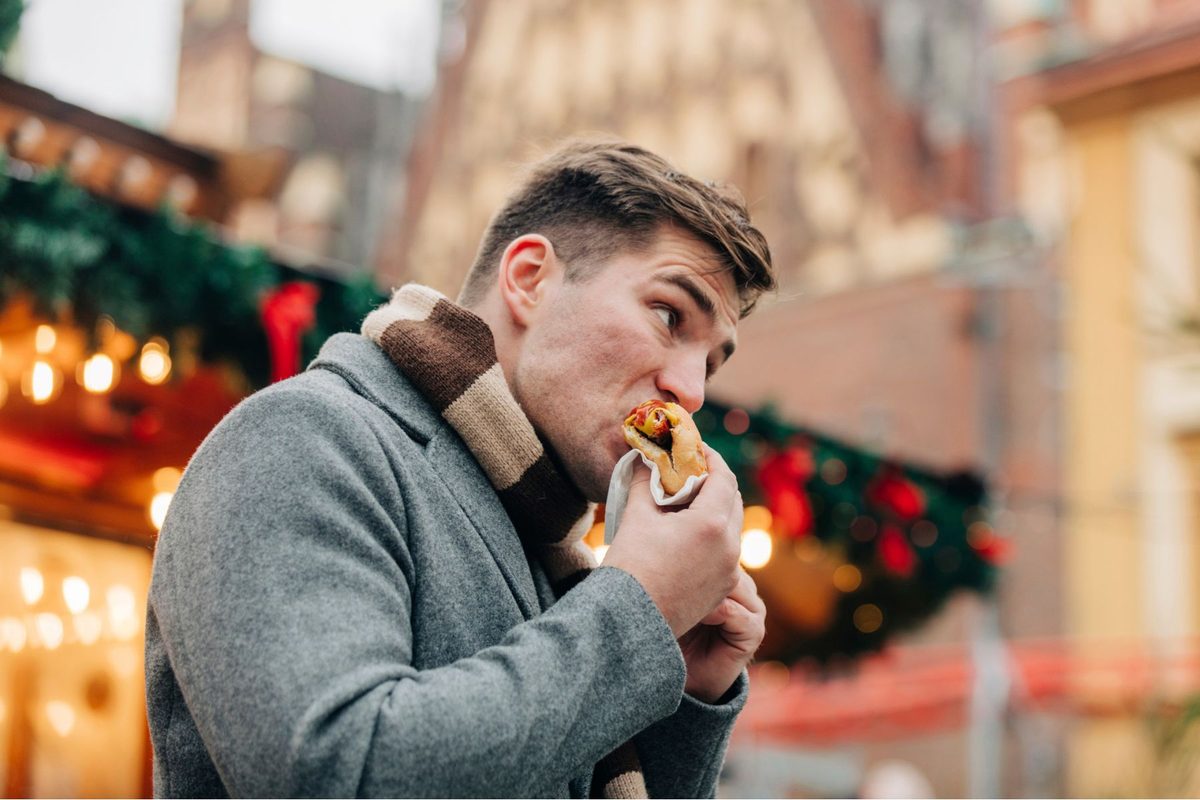 A man bites into a hotdog at a winter market