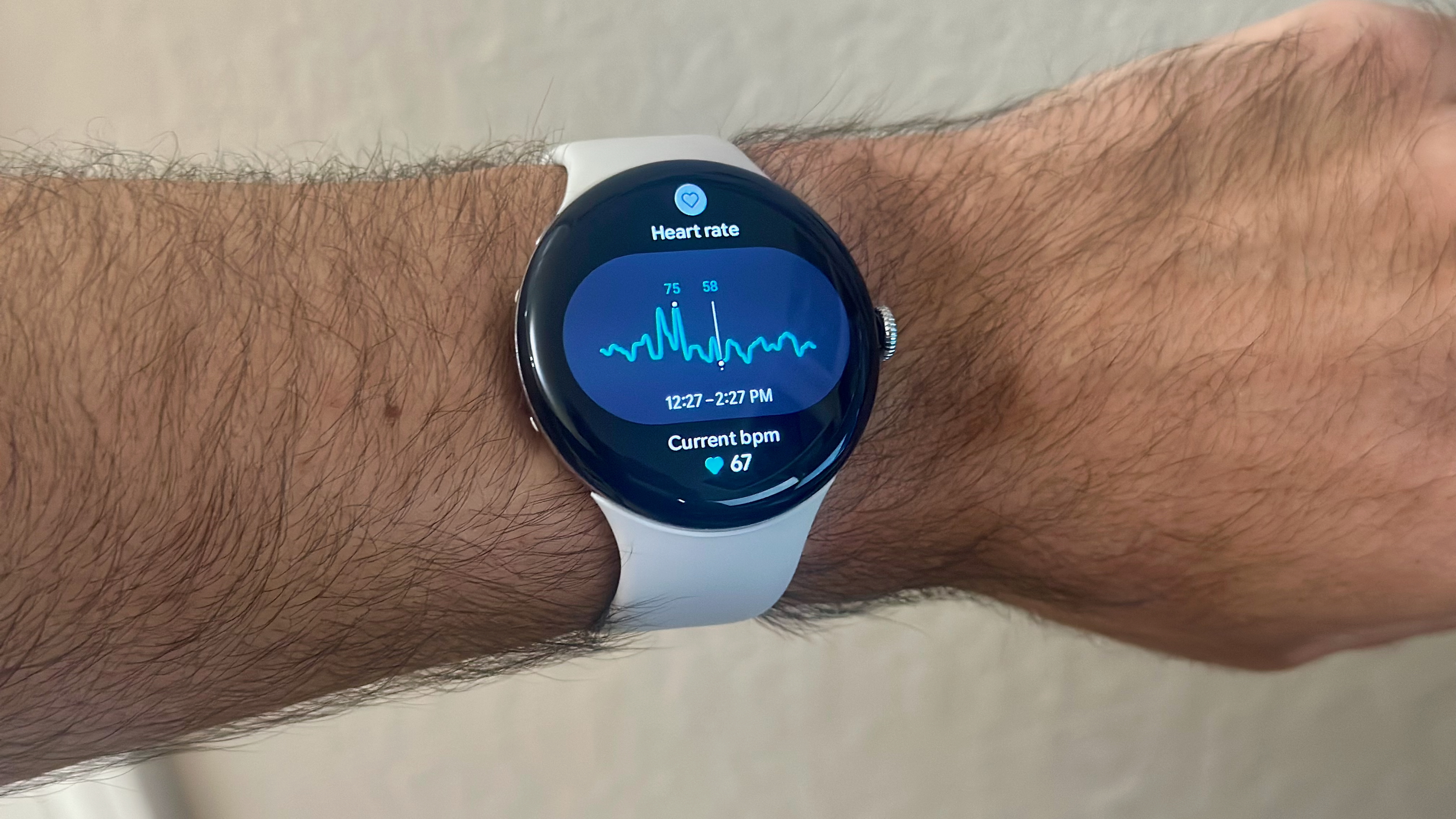 The 45mm Google Pixel Watch 4 on a man's wrist showing the Heart Rate tile, showing a HR high and low on a graph, with the current HR (66) below the graph.