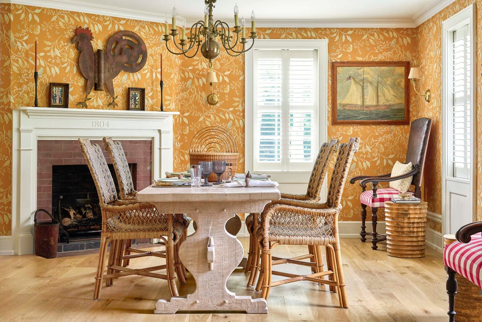 dining room with orange wallpaper, fireplace, wooden table, and rattan chairs