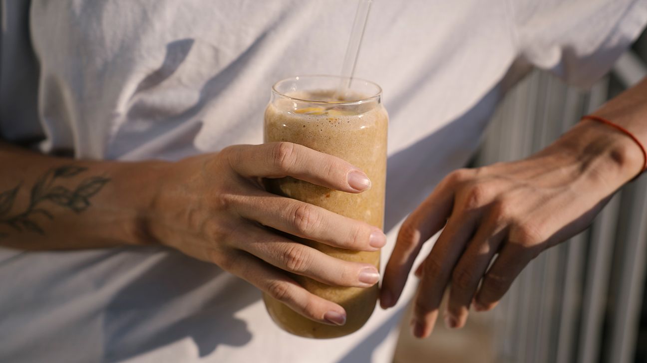 Female holding chocolate protein shake in a glass 