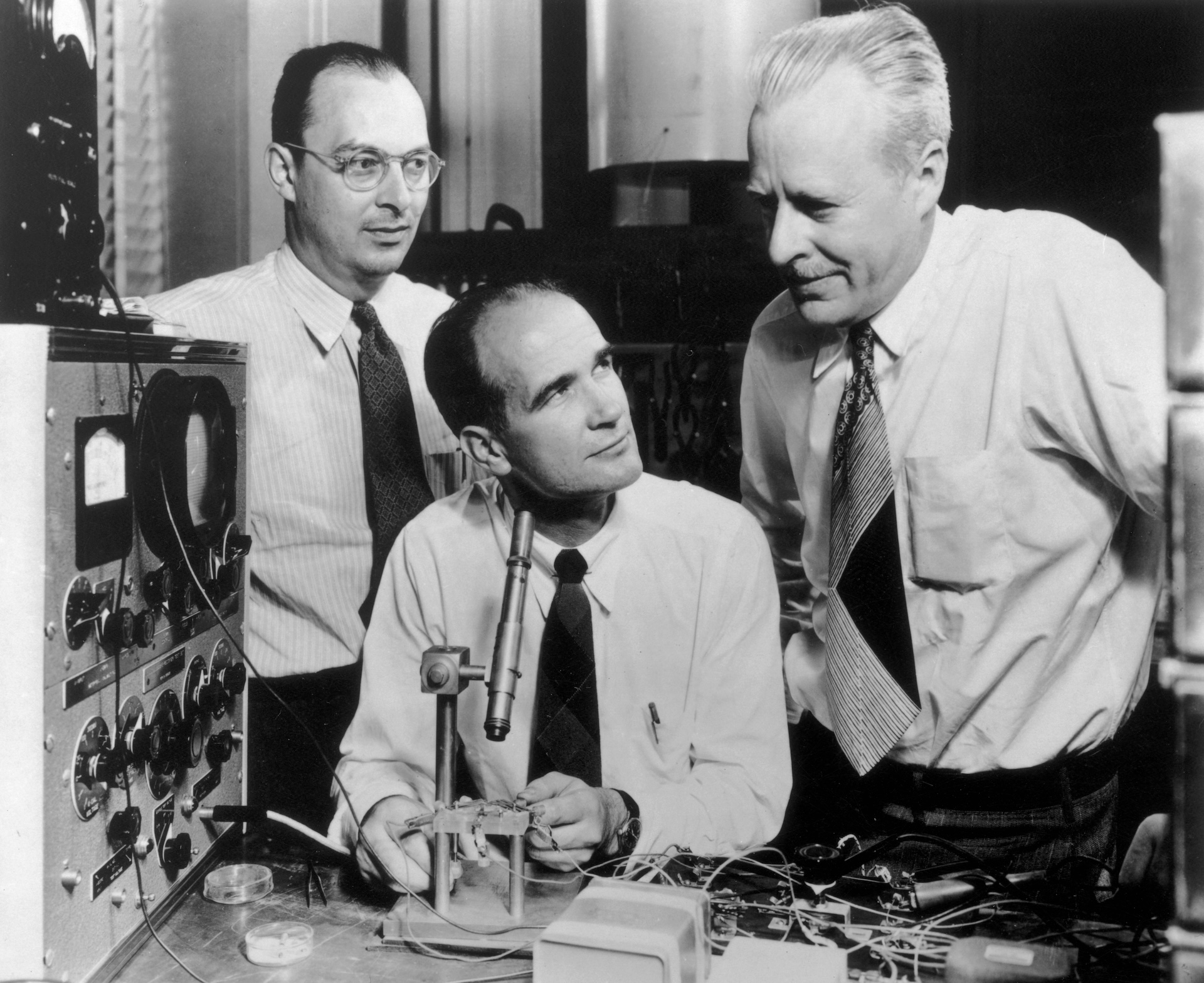 John Bardeen, William Shockley, and Walter Brattain standing at a laboratory table