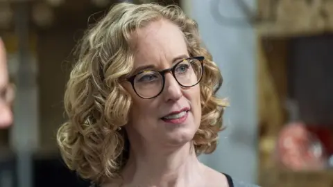 PA Media Lorna Slater, who has curly blonde hair and glasses, looks to her left in a close-up shot. She is visible from the neck up. 