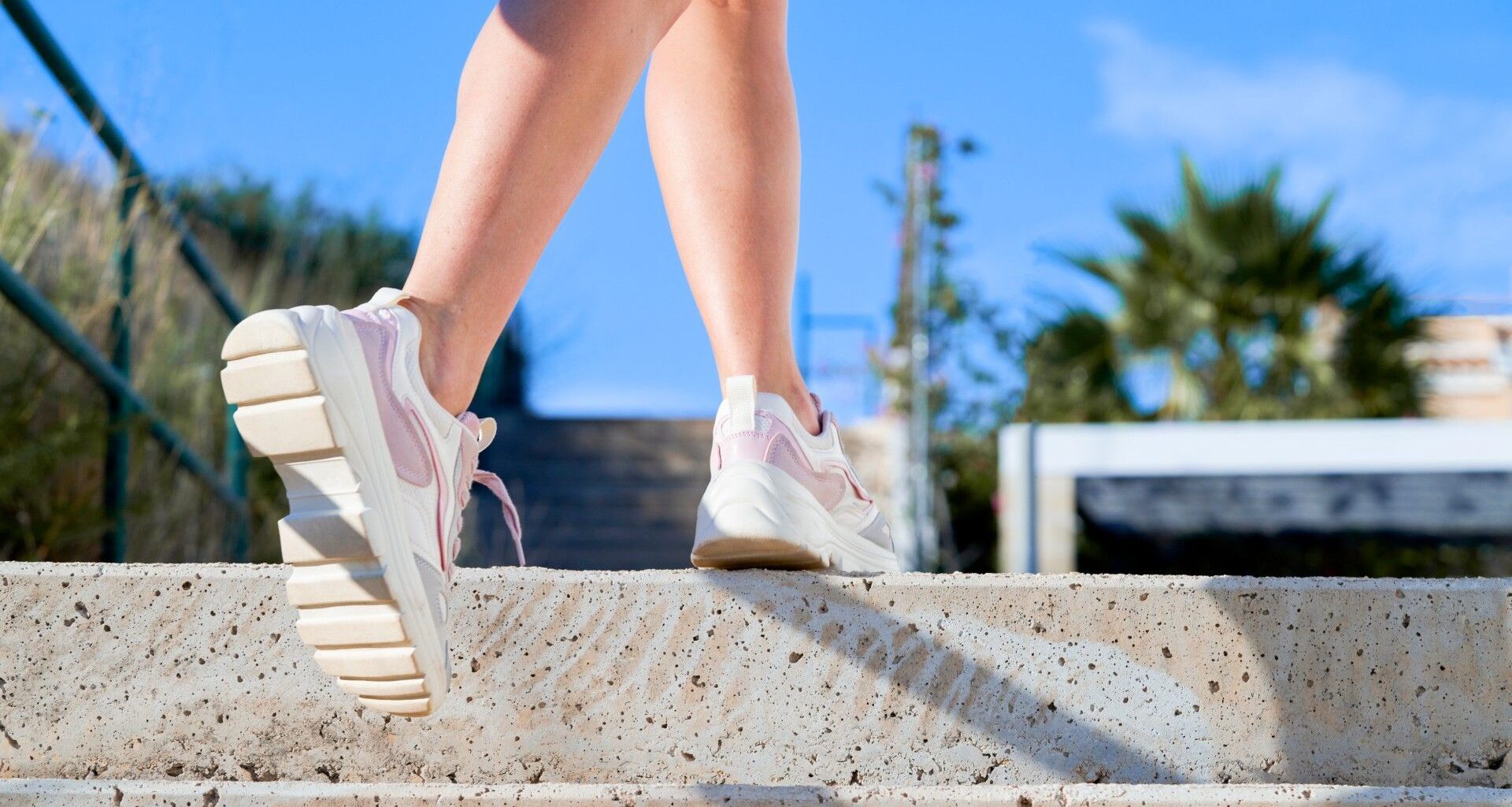 Image of someone walking up a set of stairs outdoors from knees down wearing white trainers