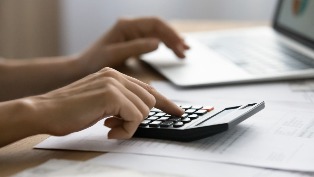 A person working on the laptop using a calculator.