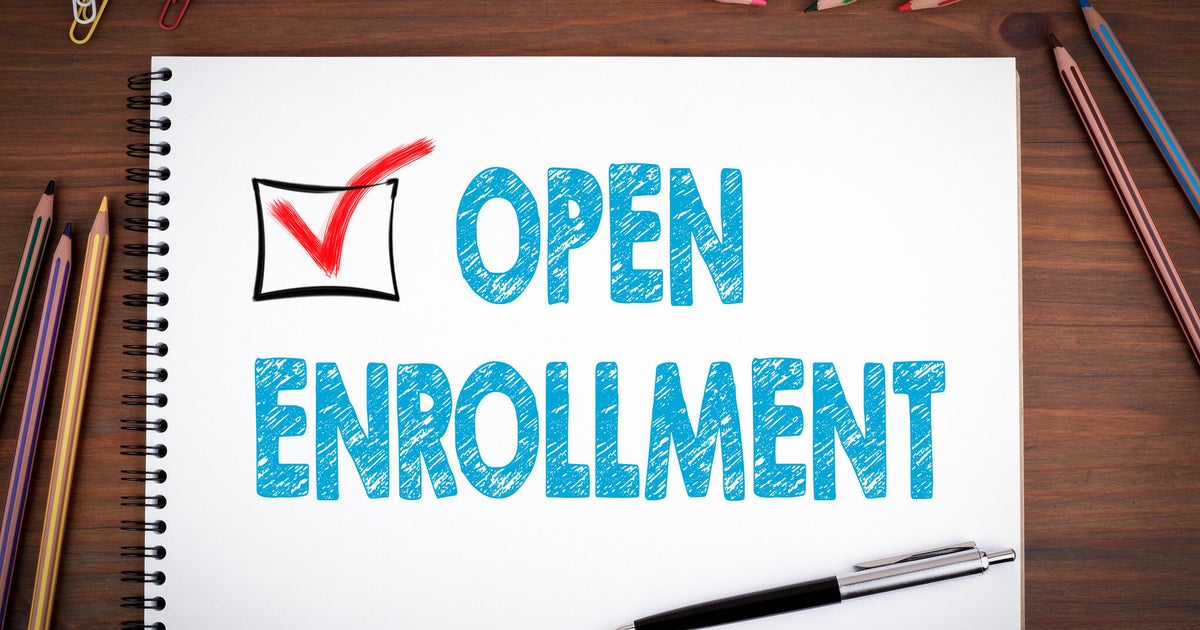 Open Enrollment. Notebooks, pen and colored pencils on a wooden table