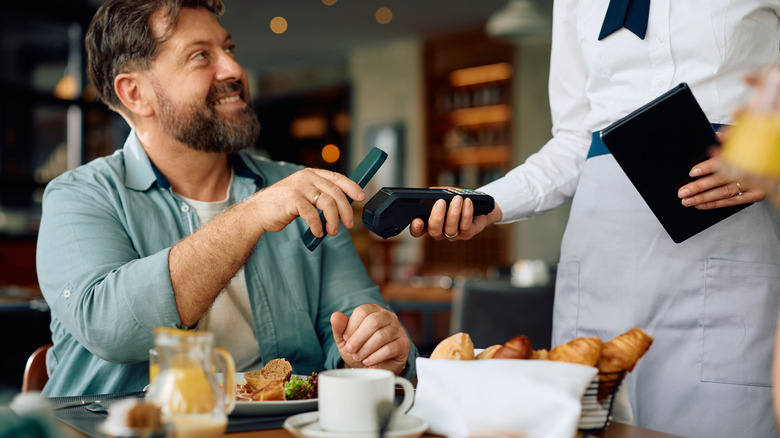 Man using a smartphone to pay at a restaurant.