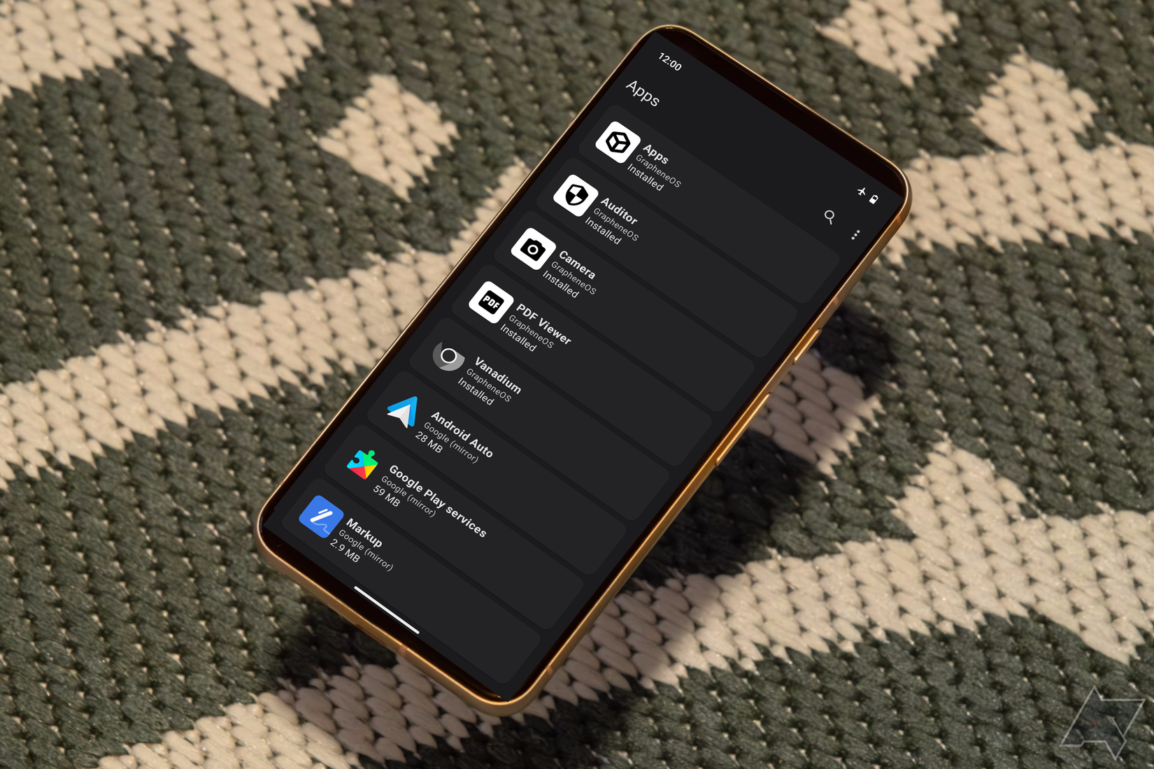 A Pixel 8 with the GrapheneOS Settings Menu sits atop a green and white textile