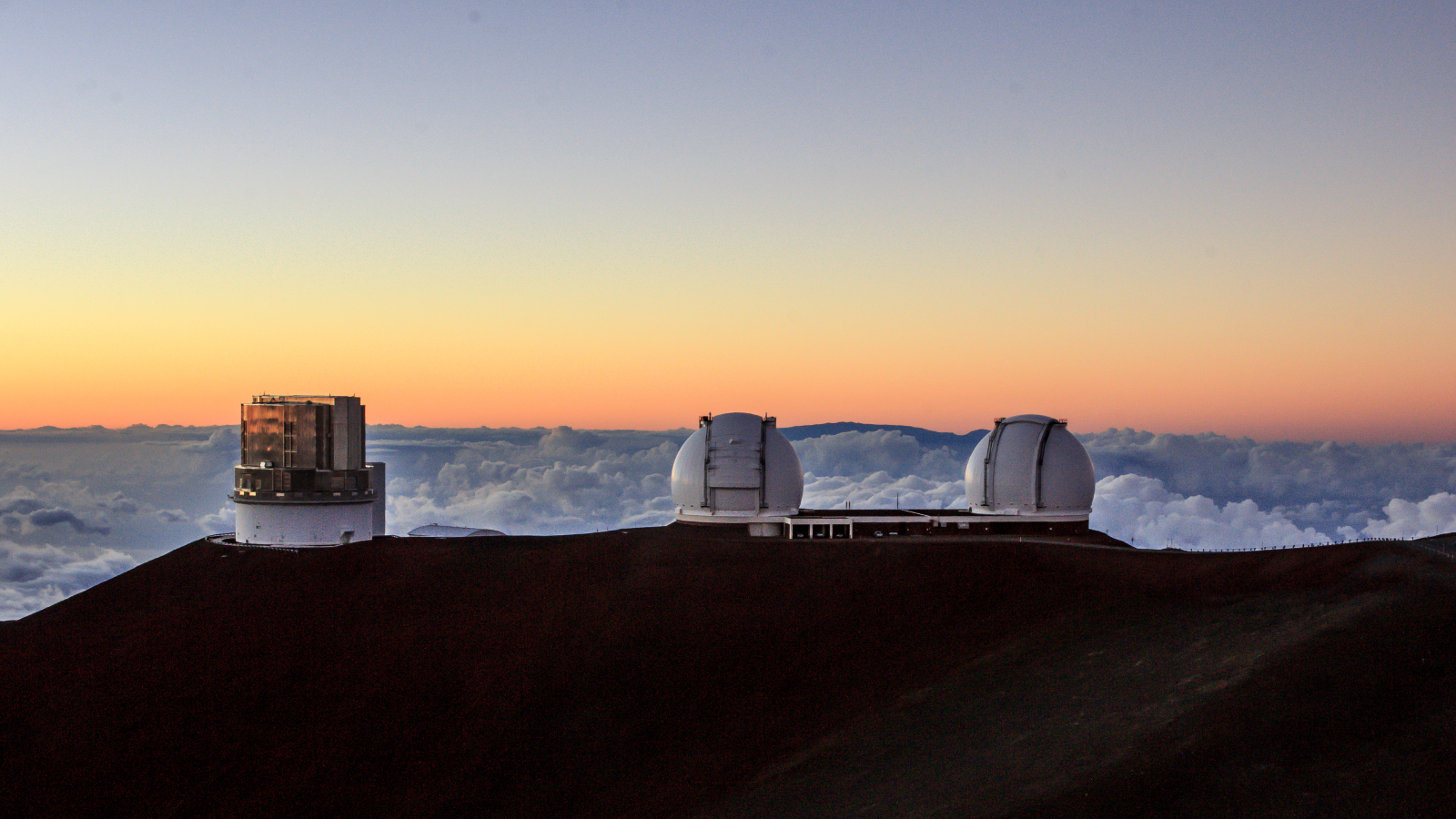 A photo of three telescopes on top of a mountain