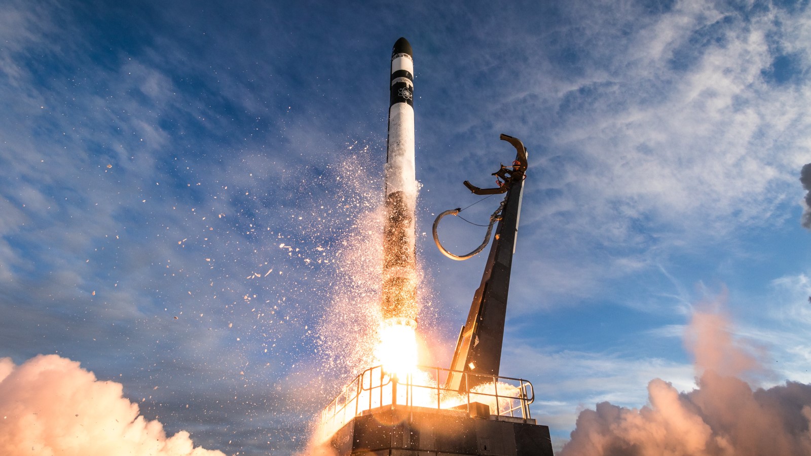 a black and white rocket launches into a cloudy blue sky