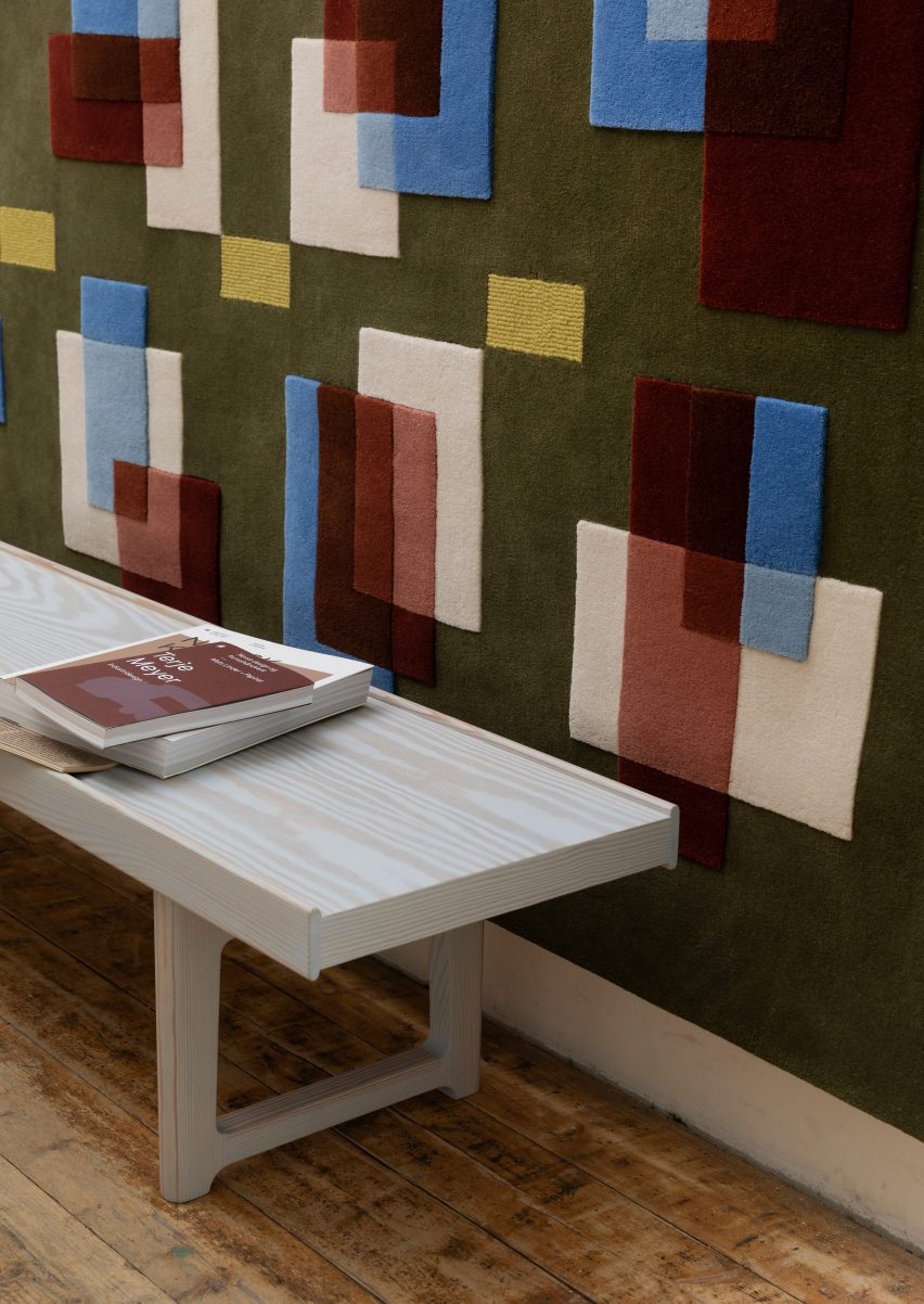 White bench in front of a wall-hung tapestry