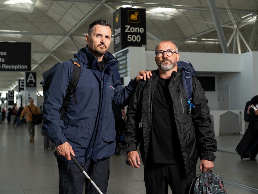 two men posing together at an airport terminal