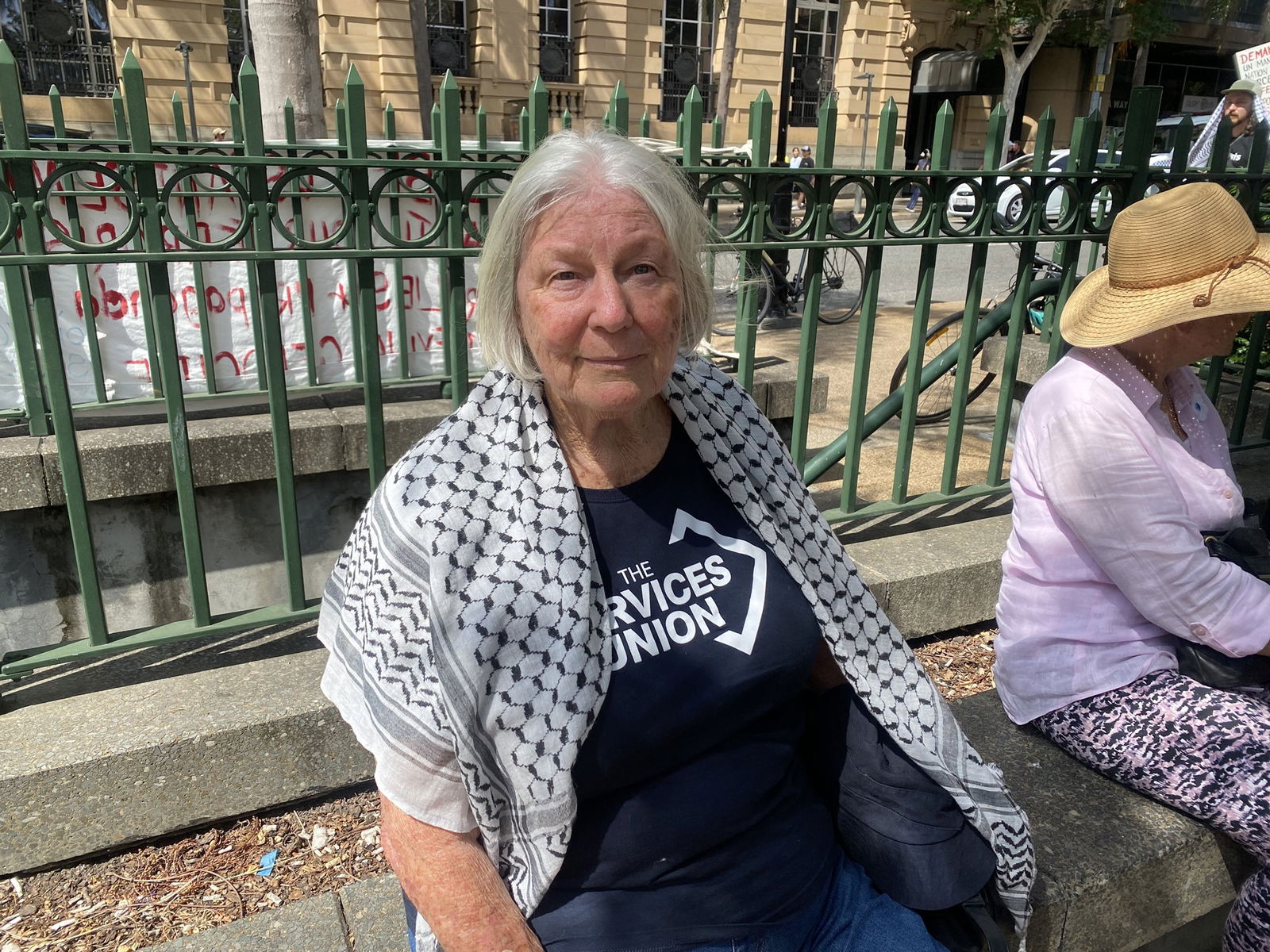 Woman with shawl sits on bench in Brisbane