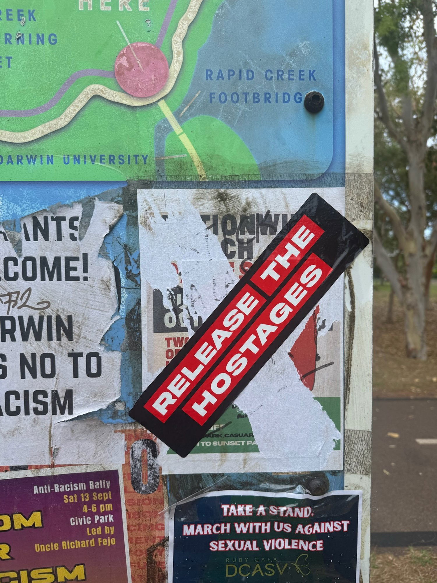 A ripped apart poster replaced with a sticker that reads: RELEASE THE HOSTAGES.