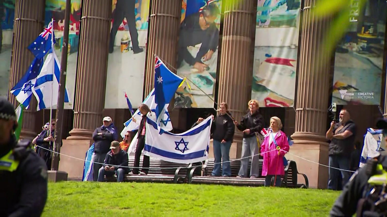 A small group of people hold up Australian and Israeli flags