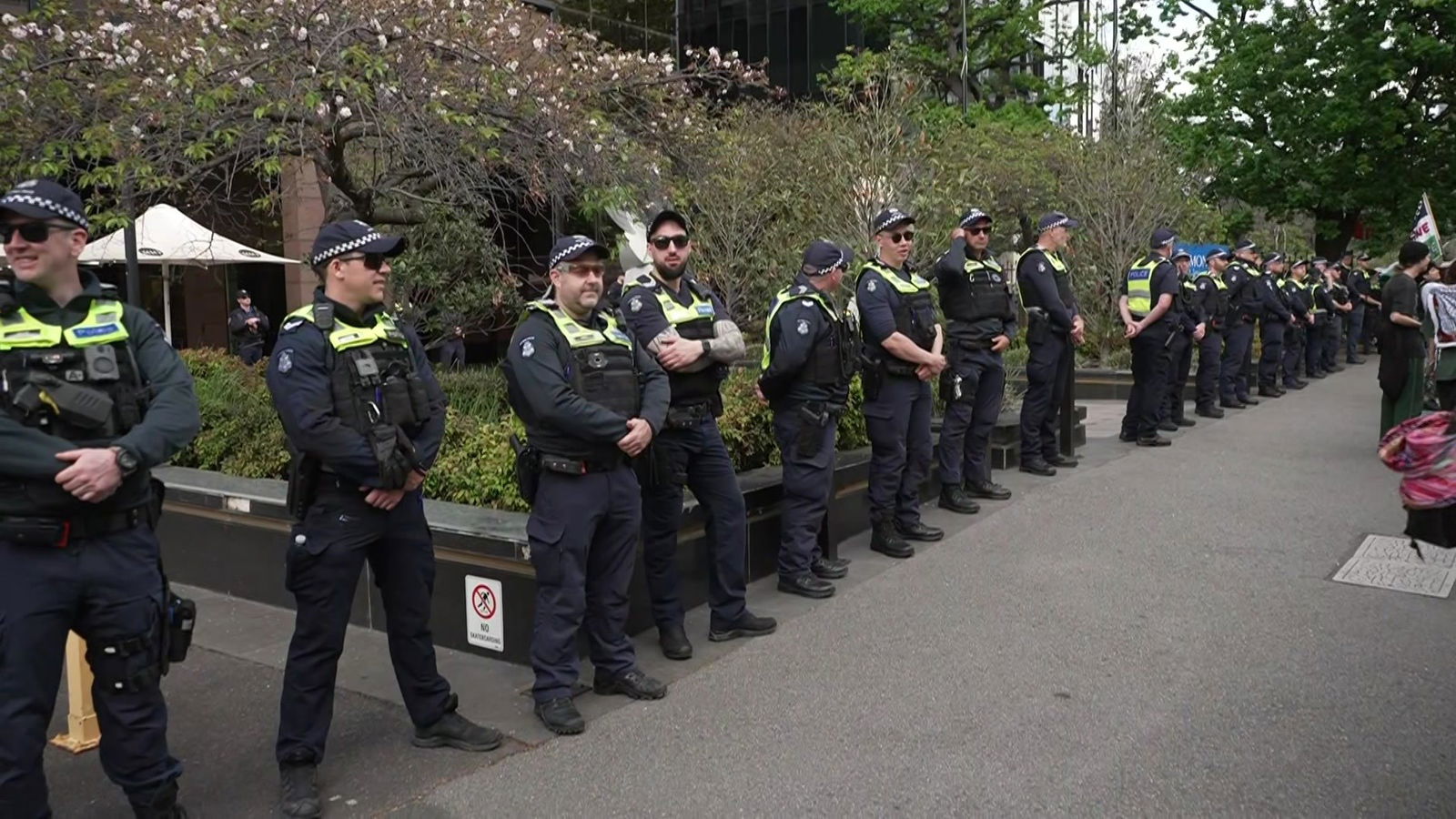 A line of police stand along a footpath