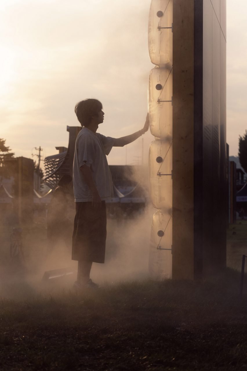 Boy standing in front of artwork giving off mist